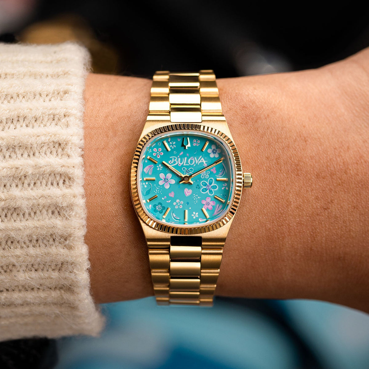 Bulova Super Seville Jardin Bleu — Custom hand-painted dial viewed at the wrist, pink blooms and small hearts drifting between gold baton markers, a bespoke timepiece by IFL Watches.