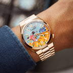 Citizen Tsuyosa Dive in Time on wrist — hand-painted dial showing a distinguished character diving into a pile of golden treasure, worn against a blue textured sleeve on a rose gold-plated case and bracelet, a bespoke timepiece by IFL Watches.