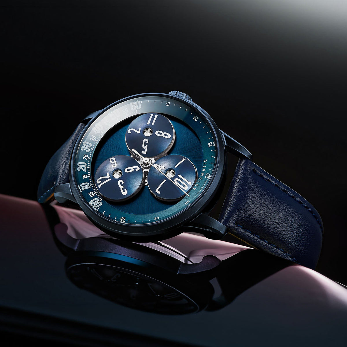 Mandetbrote Wandering Hour Dark Blue — Angled on a reflective surface, showing the case and crown, available at IFL Watches.